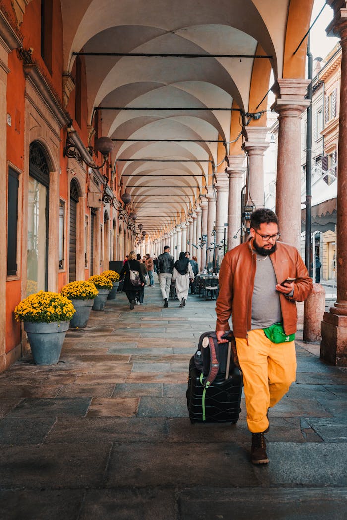Man with luggage strolling under historic arches in Verona, Italy.