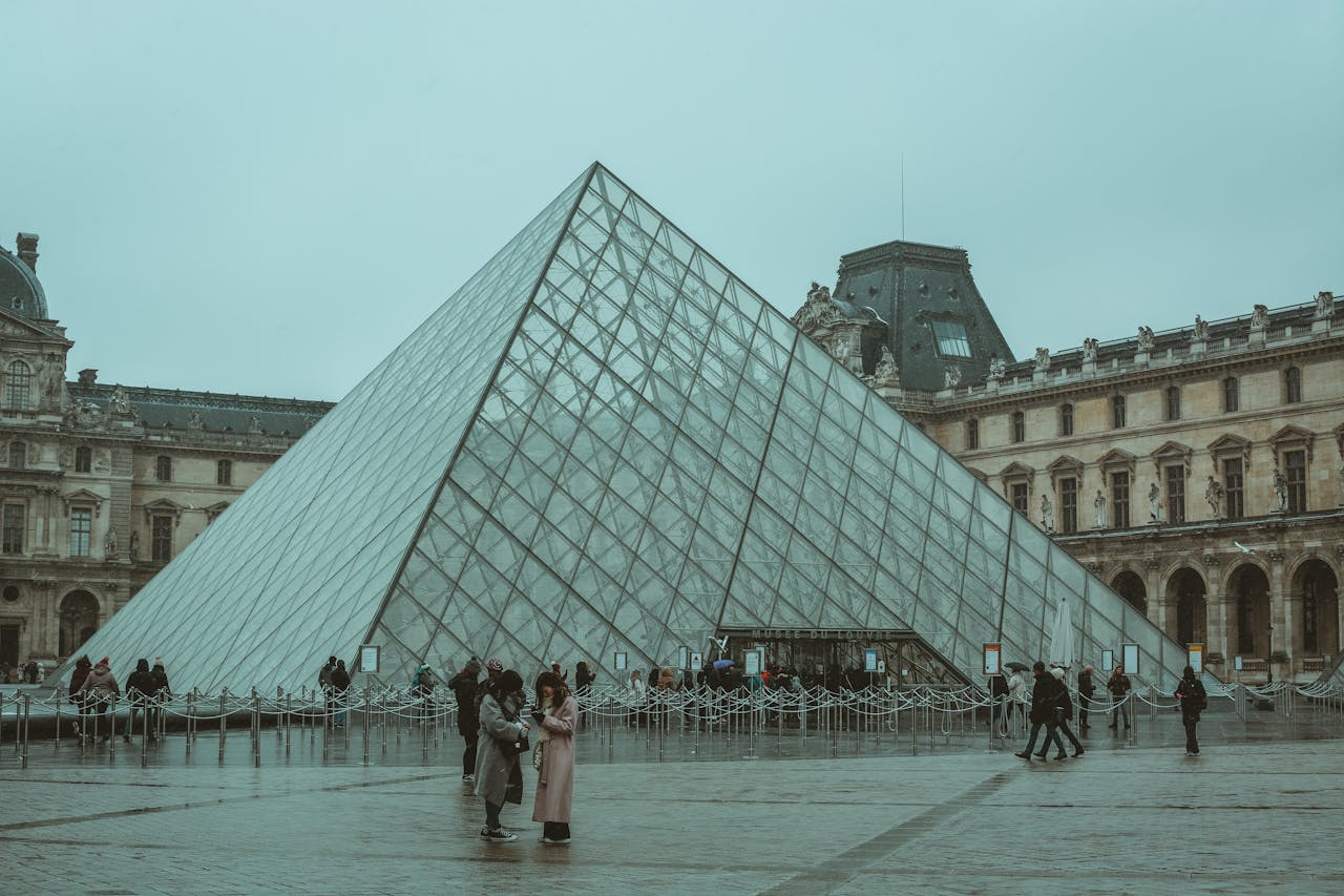 A winter day at the iconic Louvre Museum pyramid in Paris, capturing tourists and the architectural beauty.